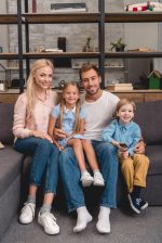 stock-photo-happy-young-family-sitting-couch-together-looking-camera